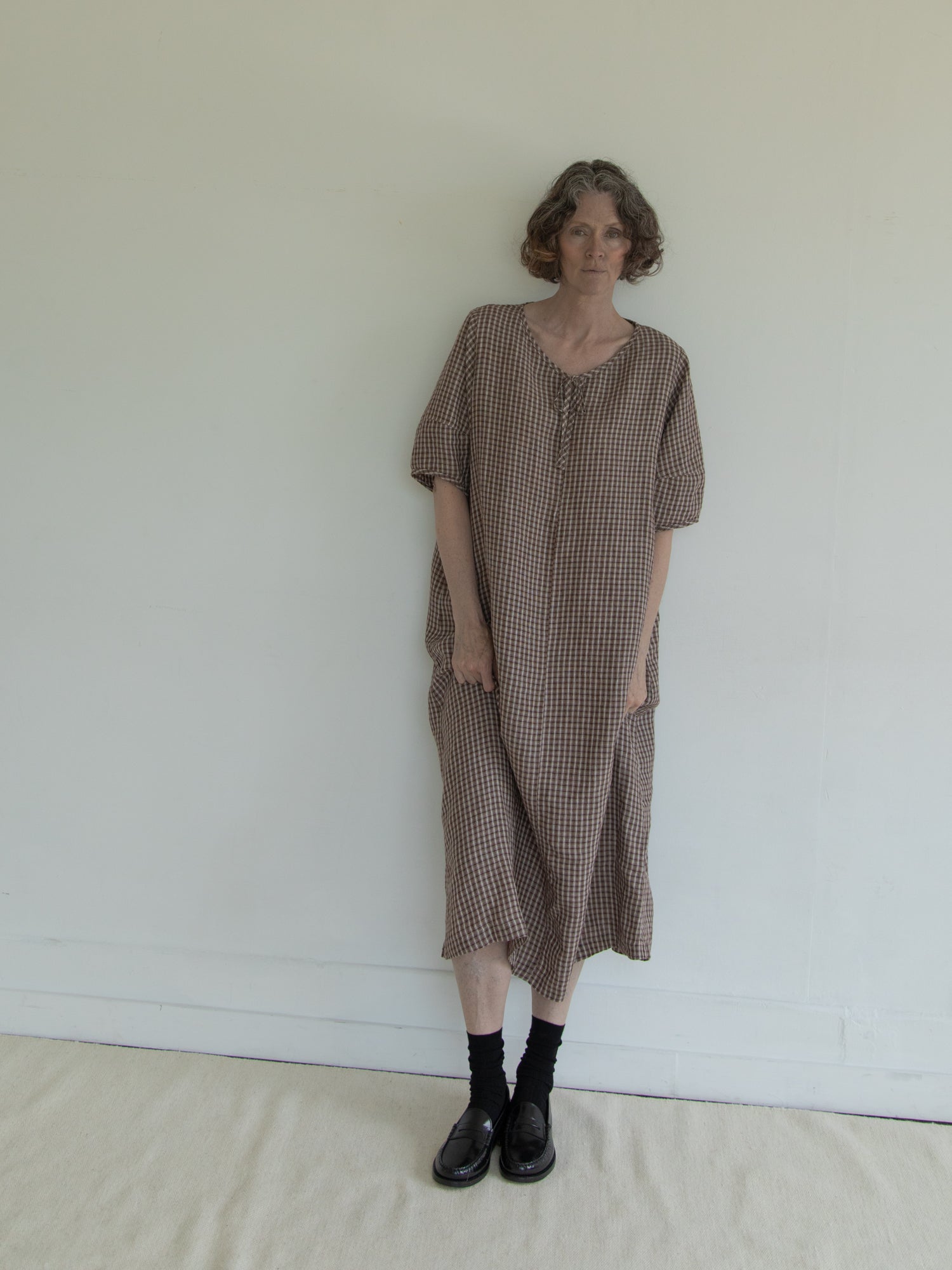 Model wearing the Blair Dress in Chocolate Plaid by Gillian Stevens, front view showing relaxed silhouette and side pockets
