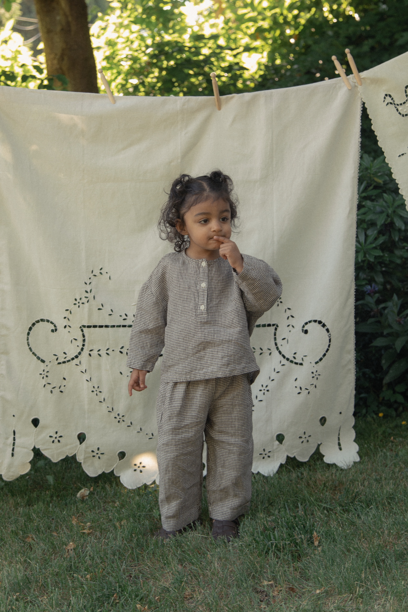 Child wearing the Bertie Top in Espresso Gingham by Gillian Stevens, front view outdoors with matching pants