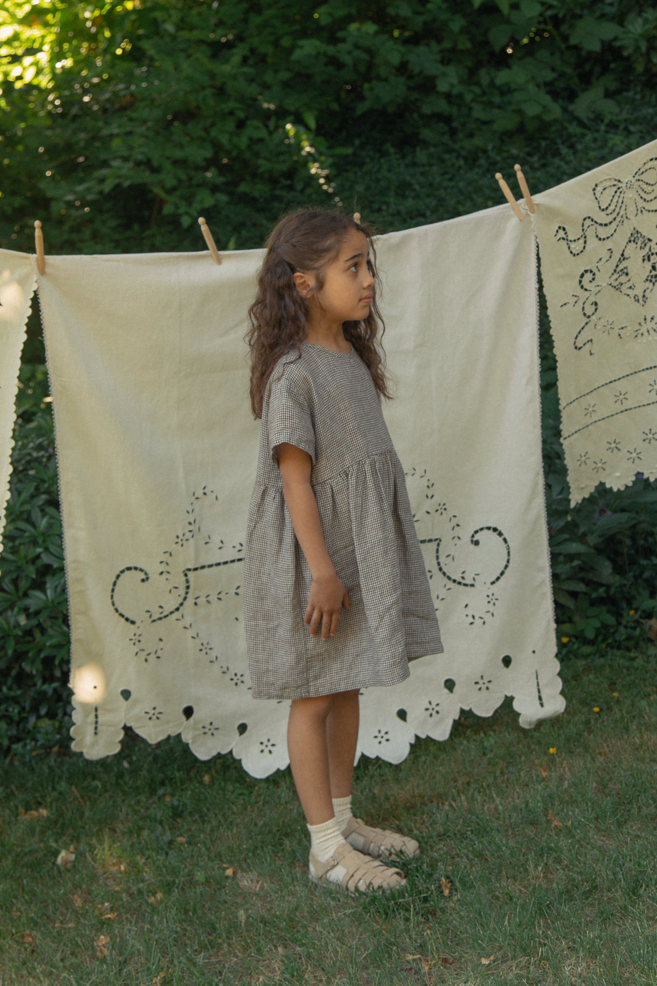 Child wearing the Mini Aya in Espresso Gingham by Gillian Stevens, side view outdoors