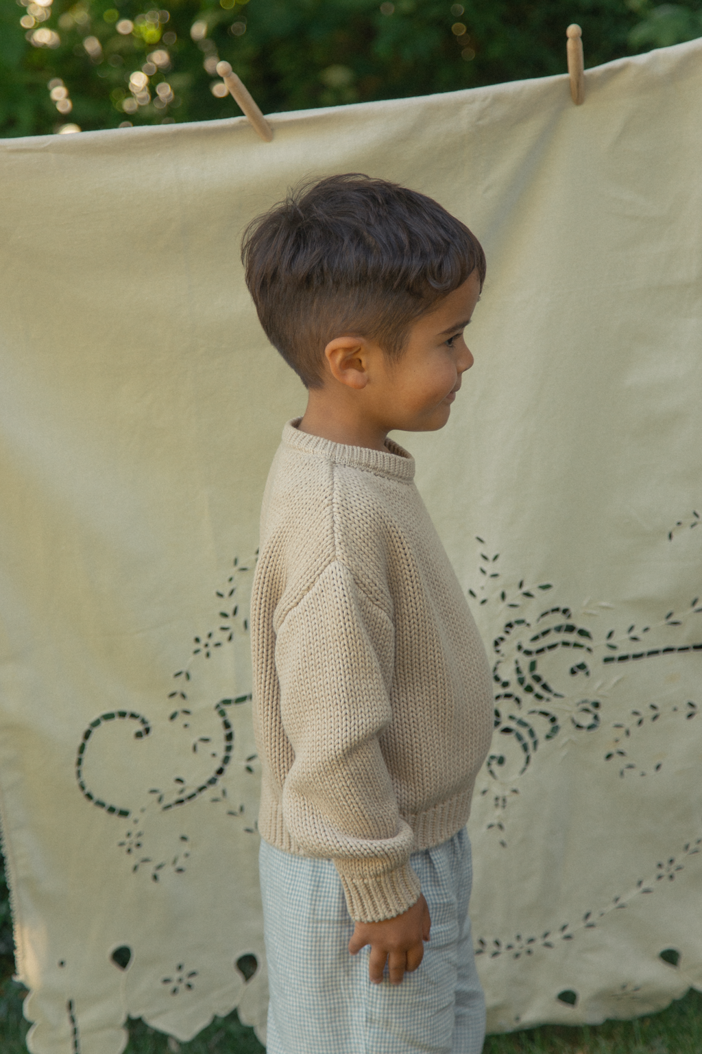 Child wearing the Mini Townes Pullover in Oat by Gillian Stevens, side view showing chunky knit texture and ribbed cuffs