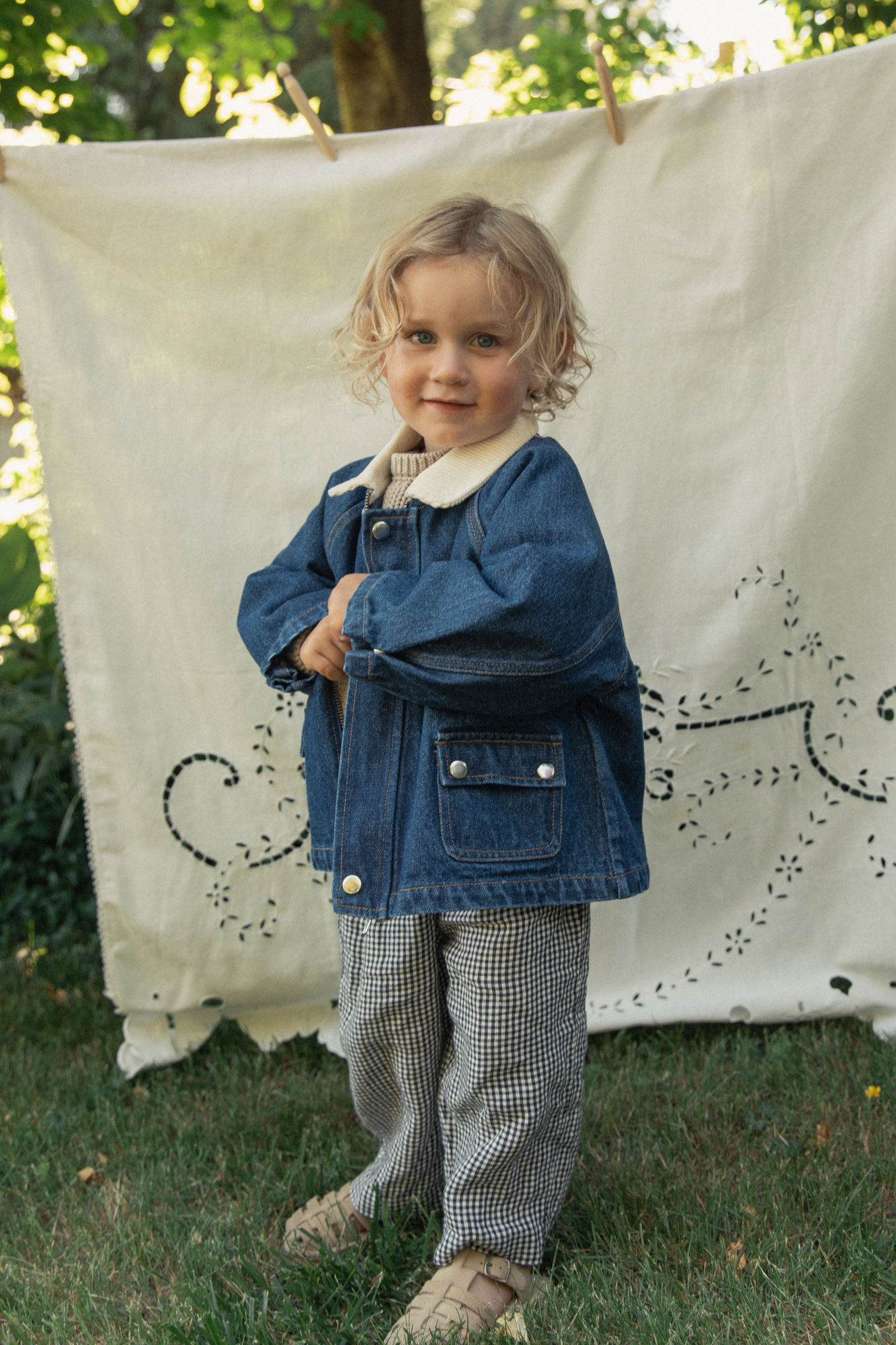 Child wearing the Brooks Jacket in Indigo by Gillian Stevens, front view styled outdoors with gingham trousers