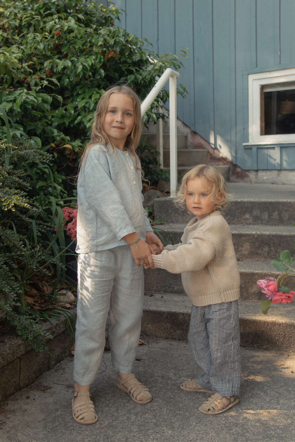 Child wearing the Bertie Pant in Pale Blue Gingham by Gillian Stevens, front view outdoors on steps