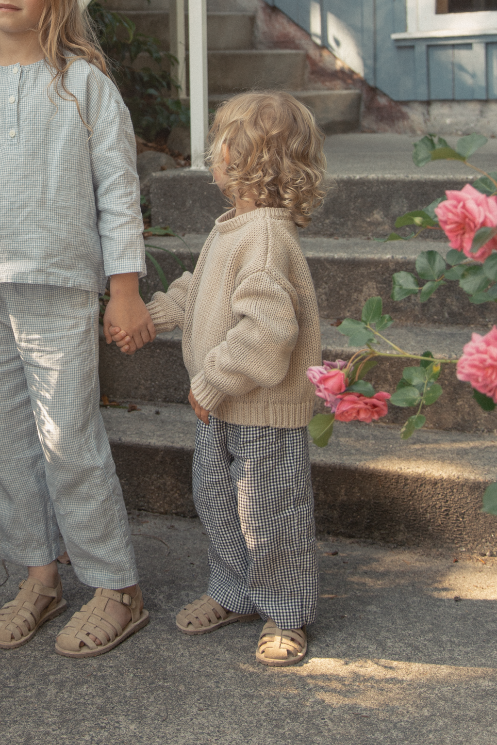 Child wearing the Bertie Pant in Marine Gingham by Gillian Stevens, back view styled with a knit sweater outdoors