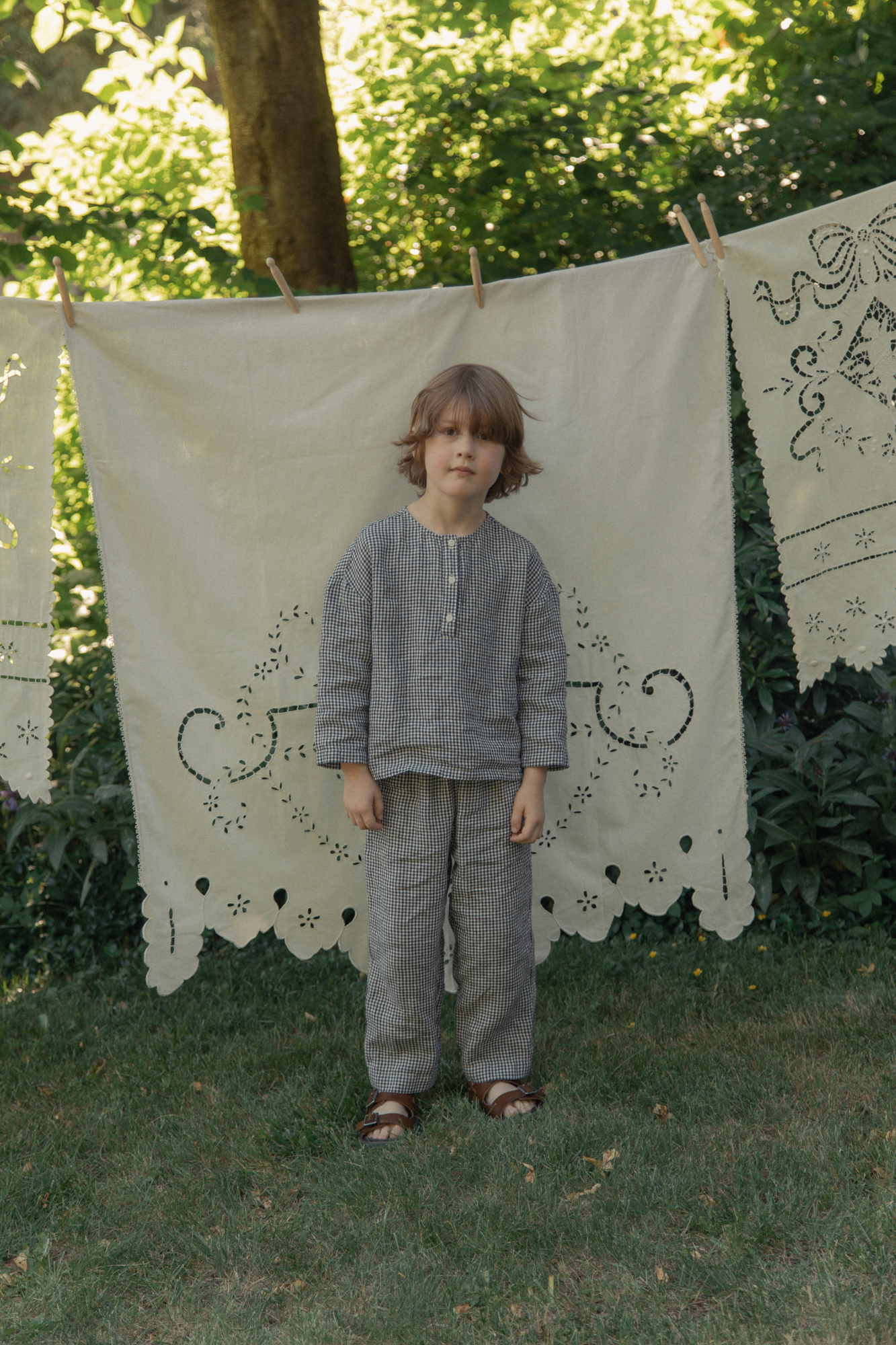 Child wearing the Bertie Pant in Marine Gingham by Gillian Stevens, full-length front view in a garden setting