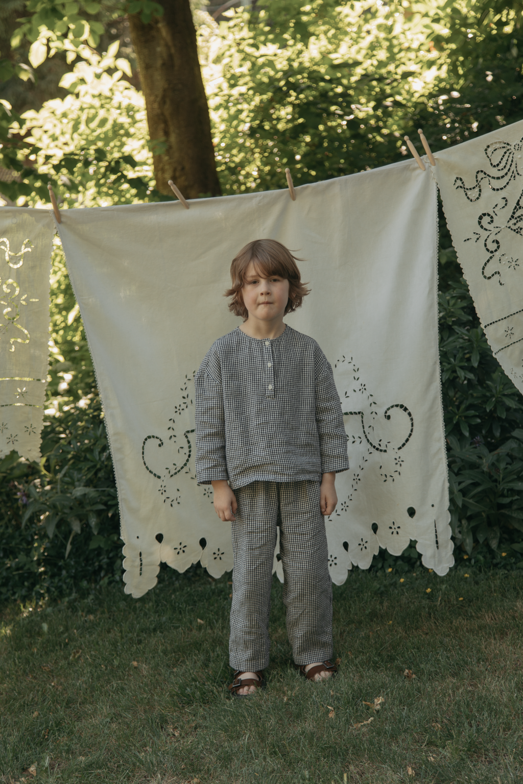 Child wearing the Bertie Pant in Marine Gingham by Gillian Stevens, full-length front view in a garden setting