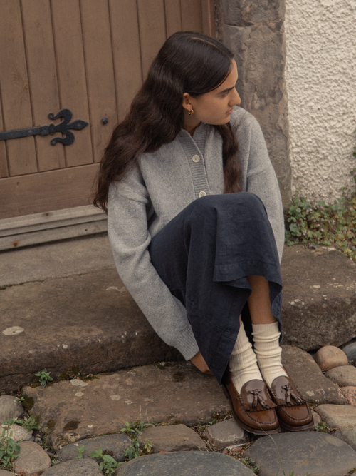 Model wearing the Allen Sock in Ivory by Gillian Stevens, styled with loafers seated on stone steps
