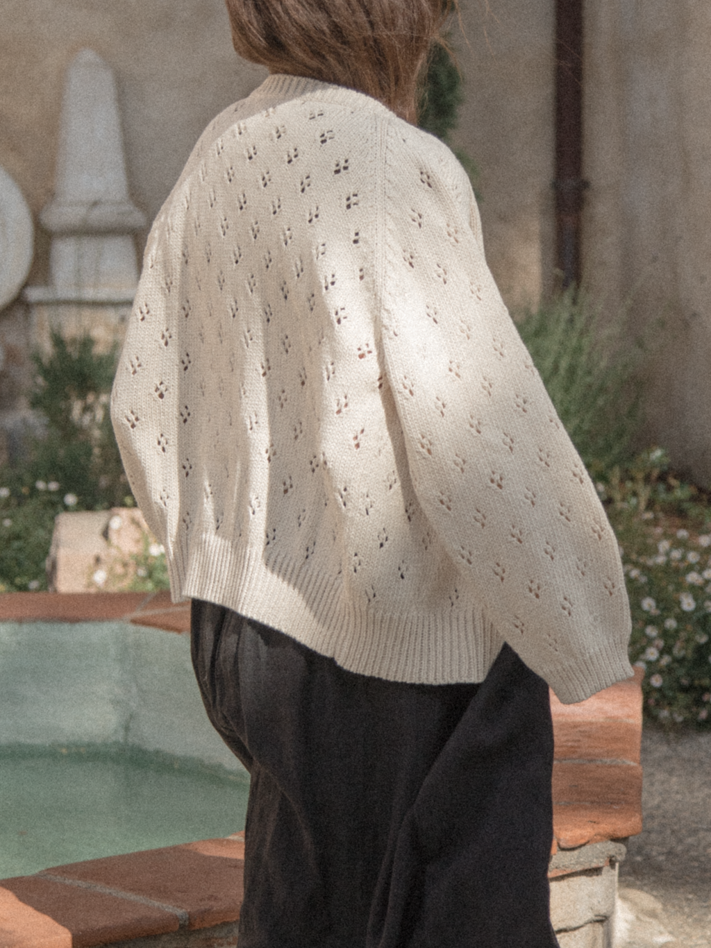 Model wearing the Mabel Cardigan in Ivory by Gillian Stevens, back view showing pointelle knit detail