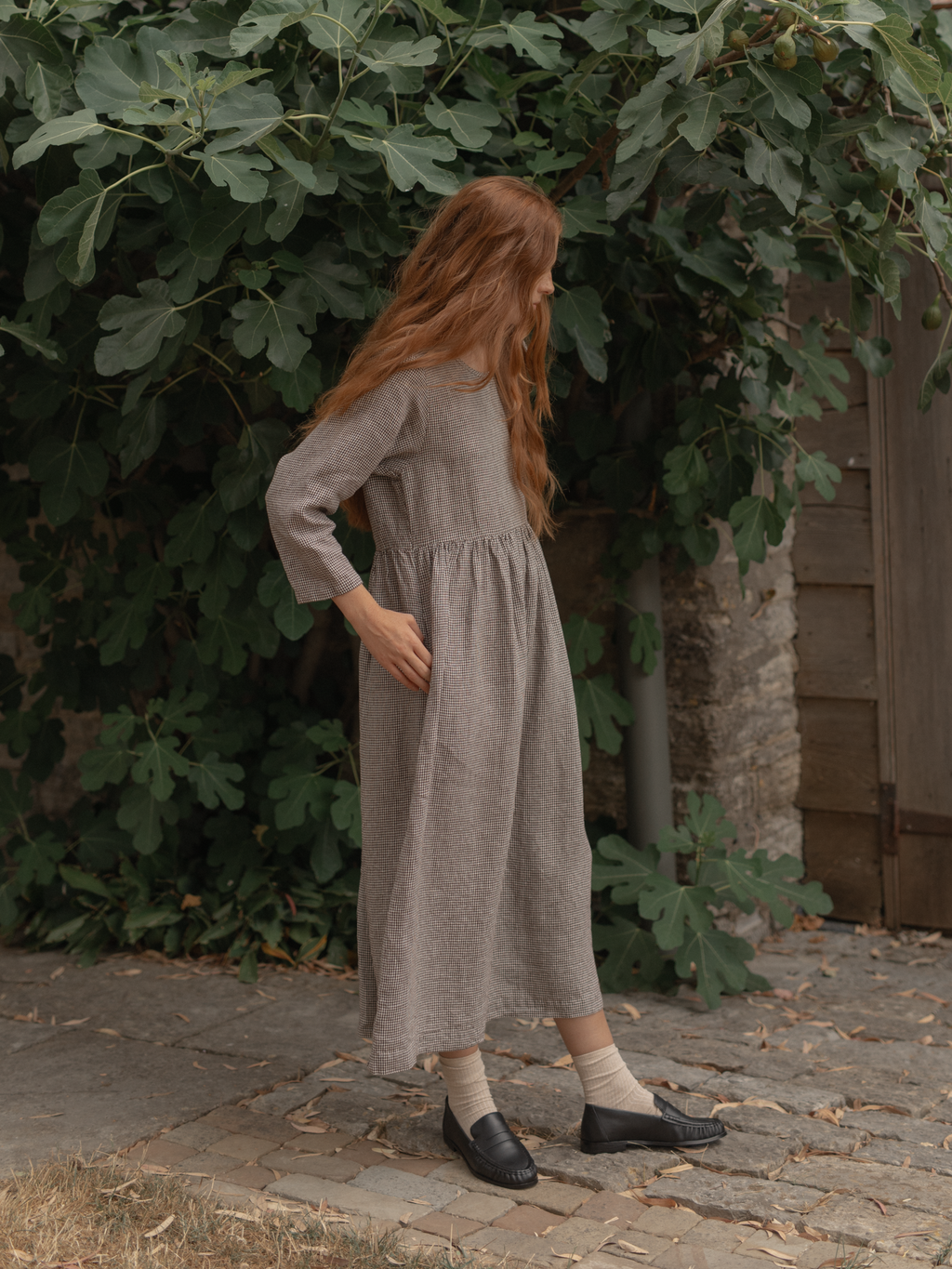 Model wearing the Artie Dress in Espresso Gingham by Gillian Stevens, side view outdoors