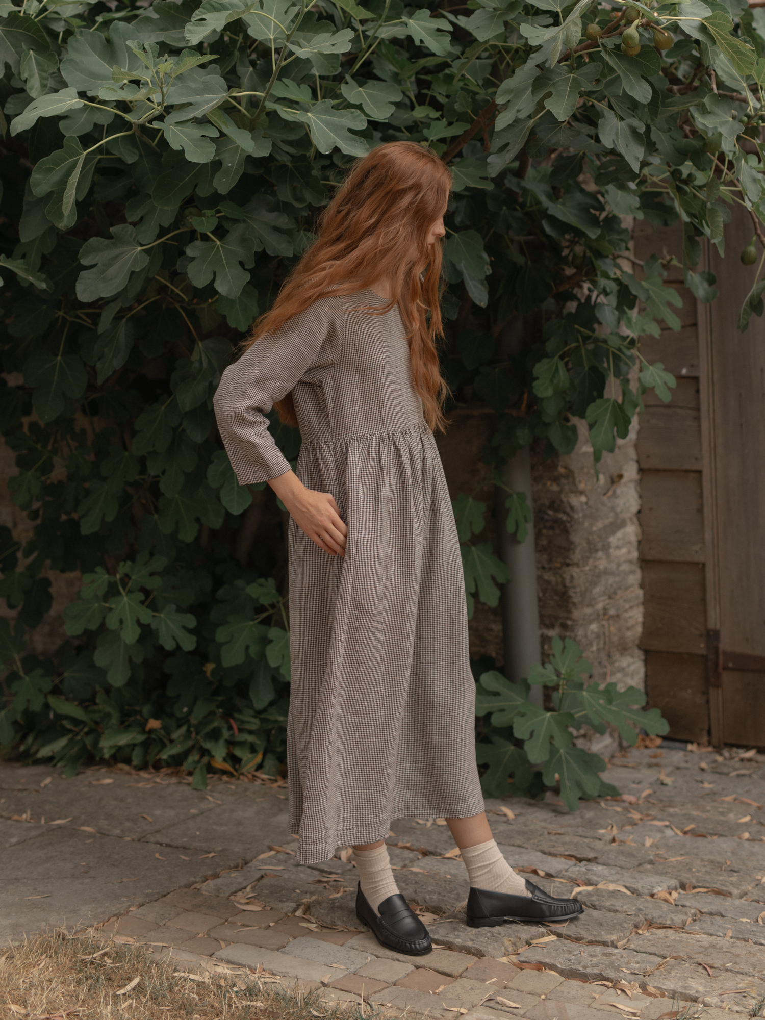 Model wearing the Artie Dress in Espresso Gingham by Gillian Stevens, side view outdoors