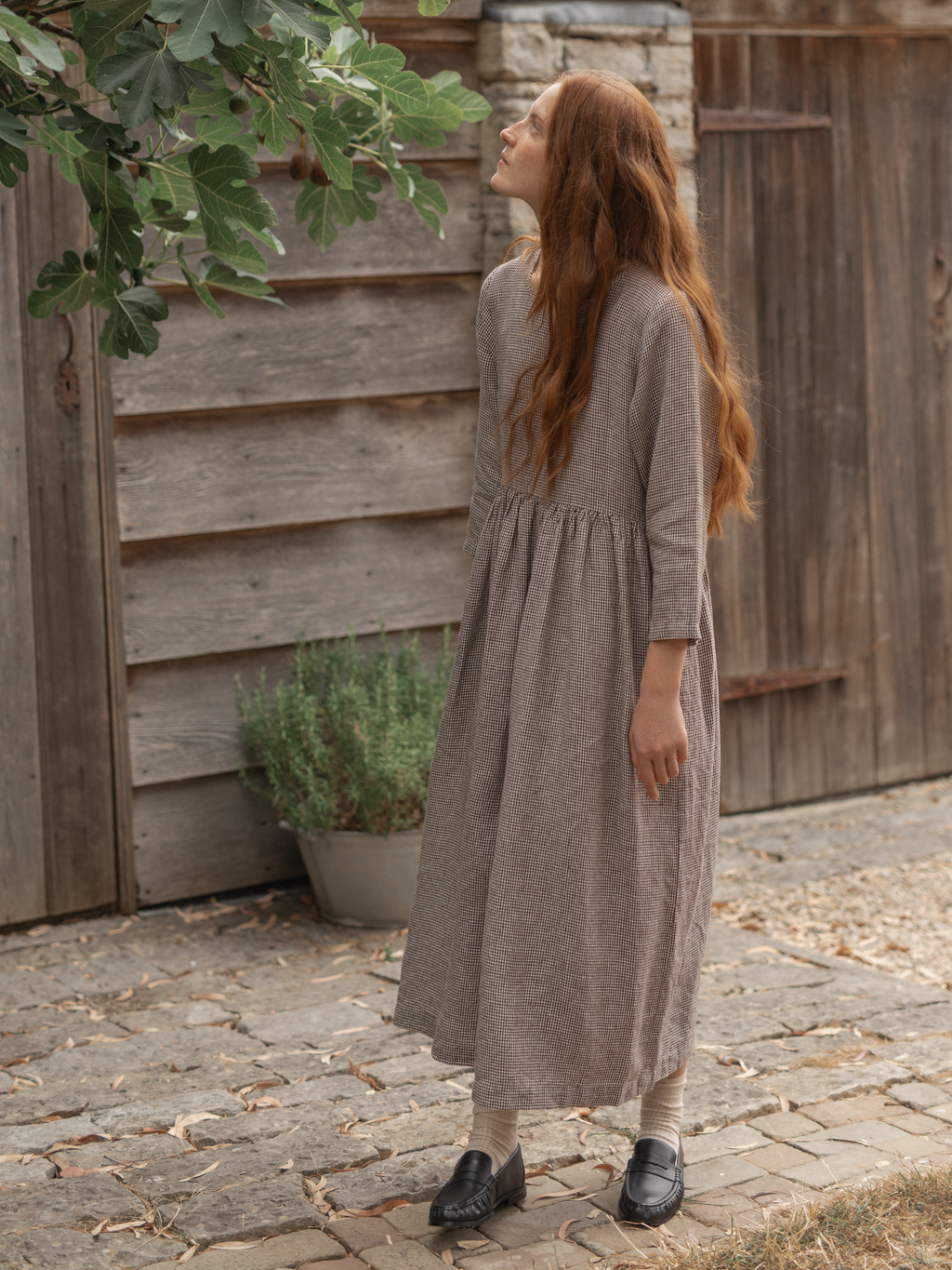 Model wearing the Artie Dress in Espresso Gingham by Gillian Stevens, back view on cobblestone path