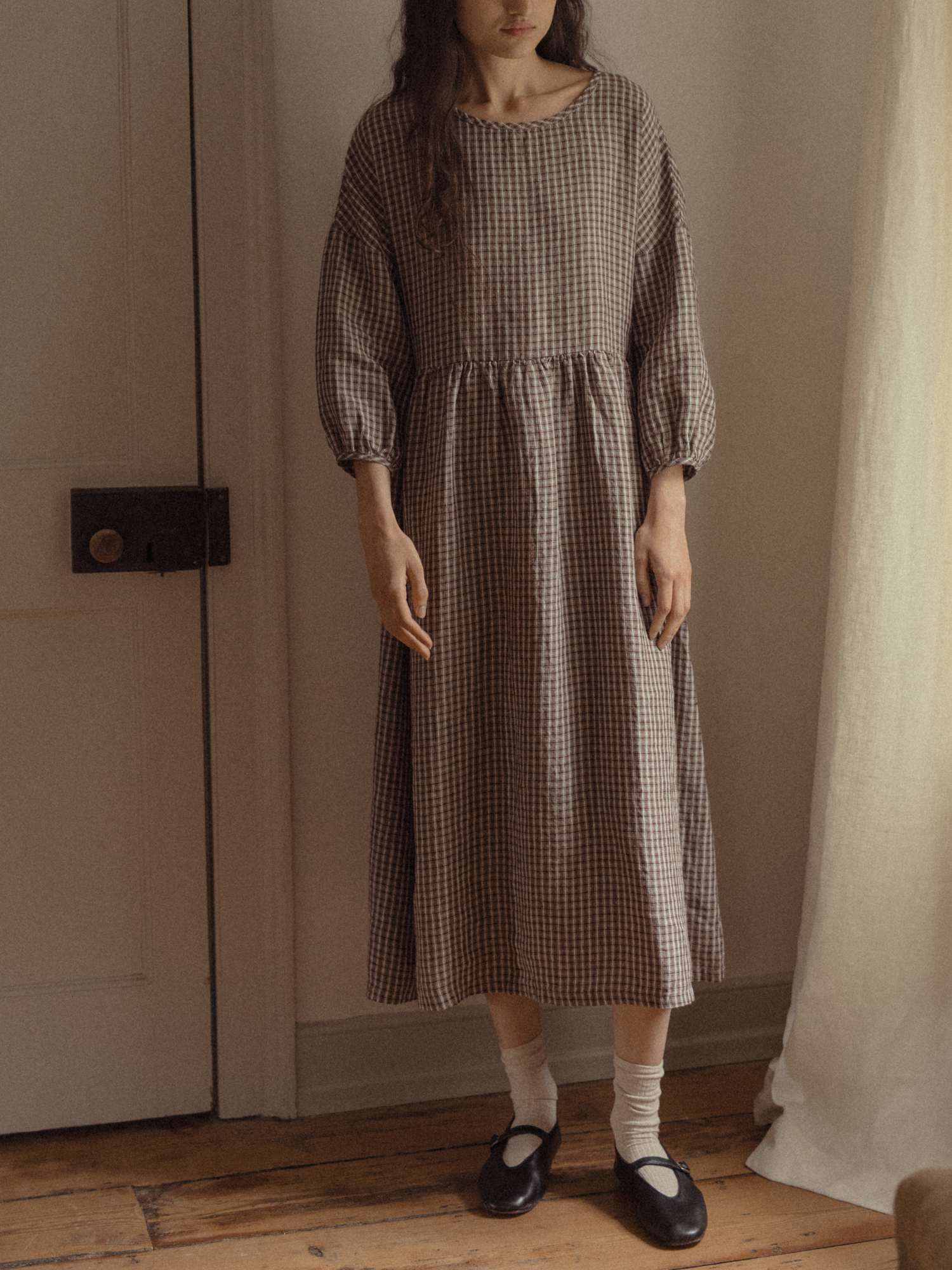 Model wearing the Darla Dress in Chocolate Plaid by Gillian Stevens, front view showing gathered waist and balloon sleeves