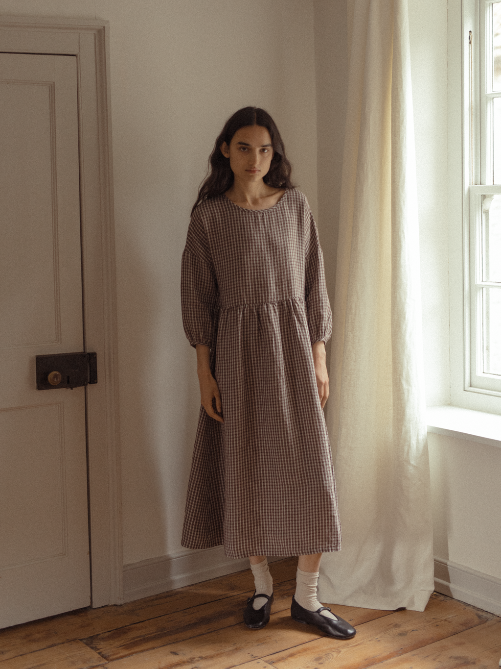 Model wearing the Darla Dress in Chocolate Plaid by Gillian Stevens, front view styled with Mary Jane flats