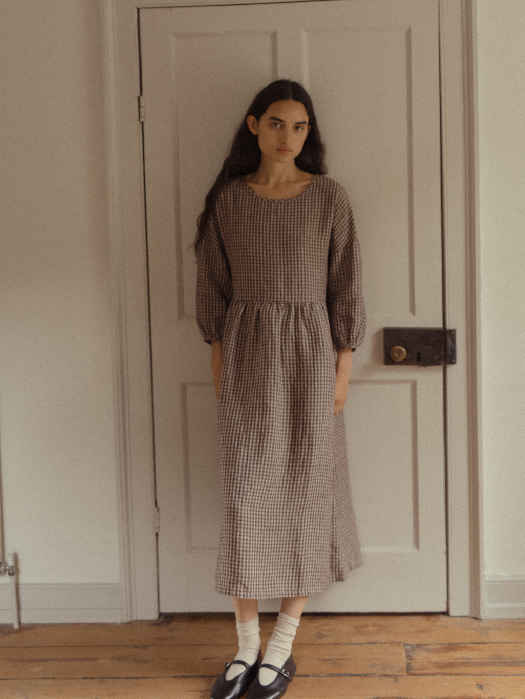 Model wearing the Darla Dress in Chocolate Plaid by Gillian Stevens, front view showing gathered waist and puff sleeves