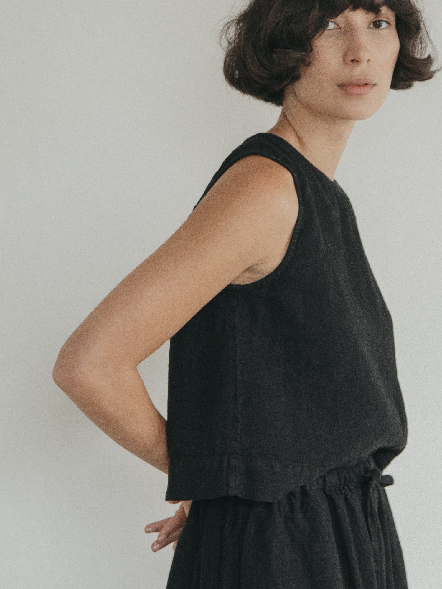 Model wearing the Finley Top in Noir by Gillian Stevens, side view showing armhole and hem detail