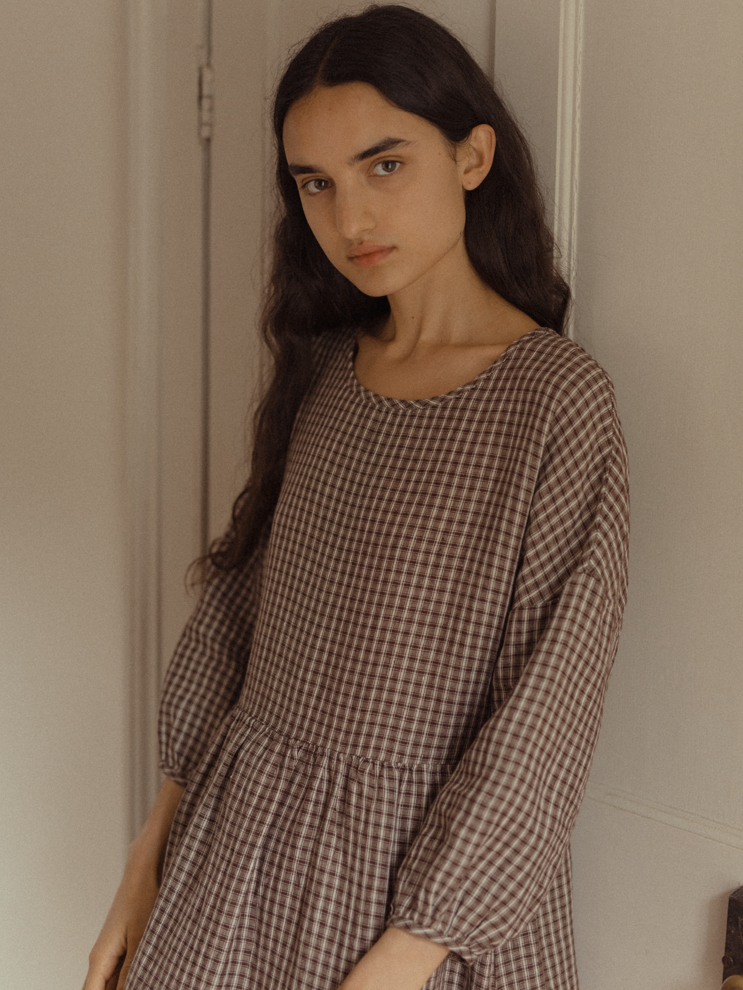Model wearing the Darla Dress in Chocolate Plaid by Gillian Stevens, angled front view showing dropped waist