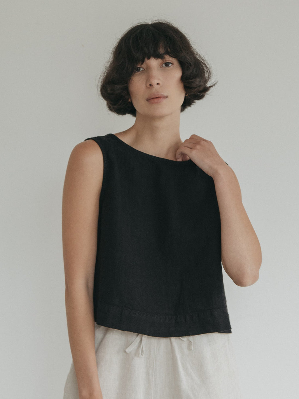 Model wearing the Finley Top in Noir by Gillian Stevens, front view with hand raised to neckline
