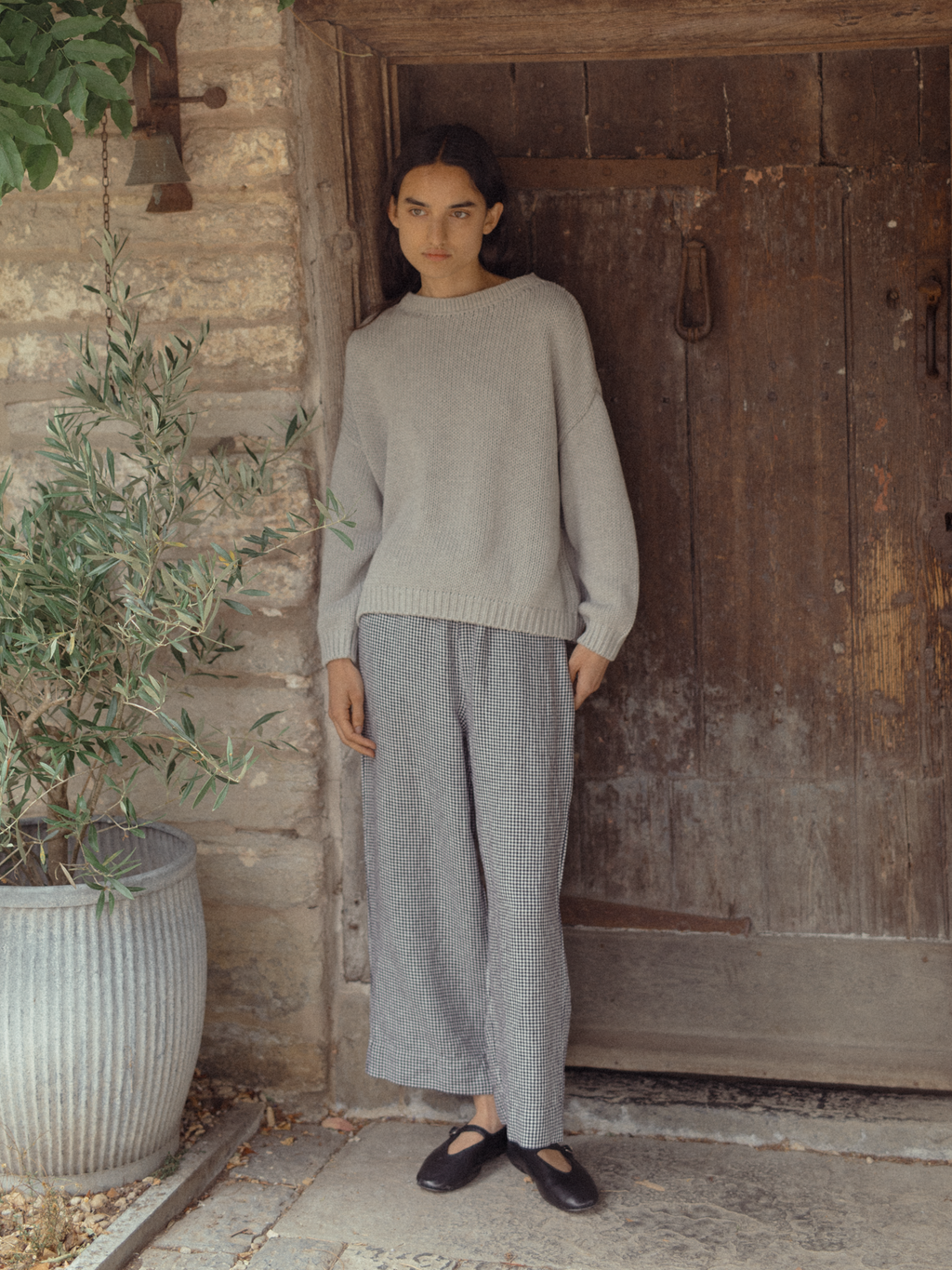 Model wearing the Olive Pant in Marine Gingham by Gillian Stevens, full-length front view by a rustic stone doorway