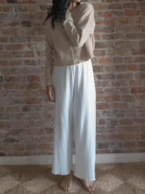 Model wearing the Calla Pant in Salt by Gillian Stevens, side view showing pleated detail against brick wall