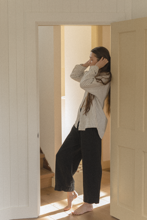 Model wearing the Britta Shirt Linen in Vintage Stripe by Gillian Stevens, side profile in doorway
