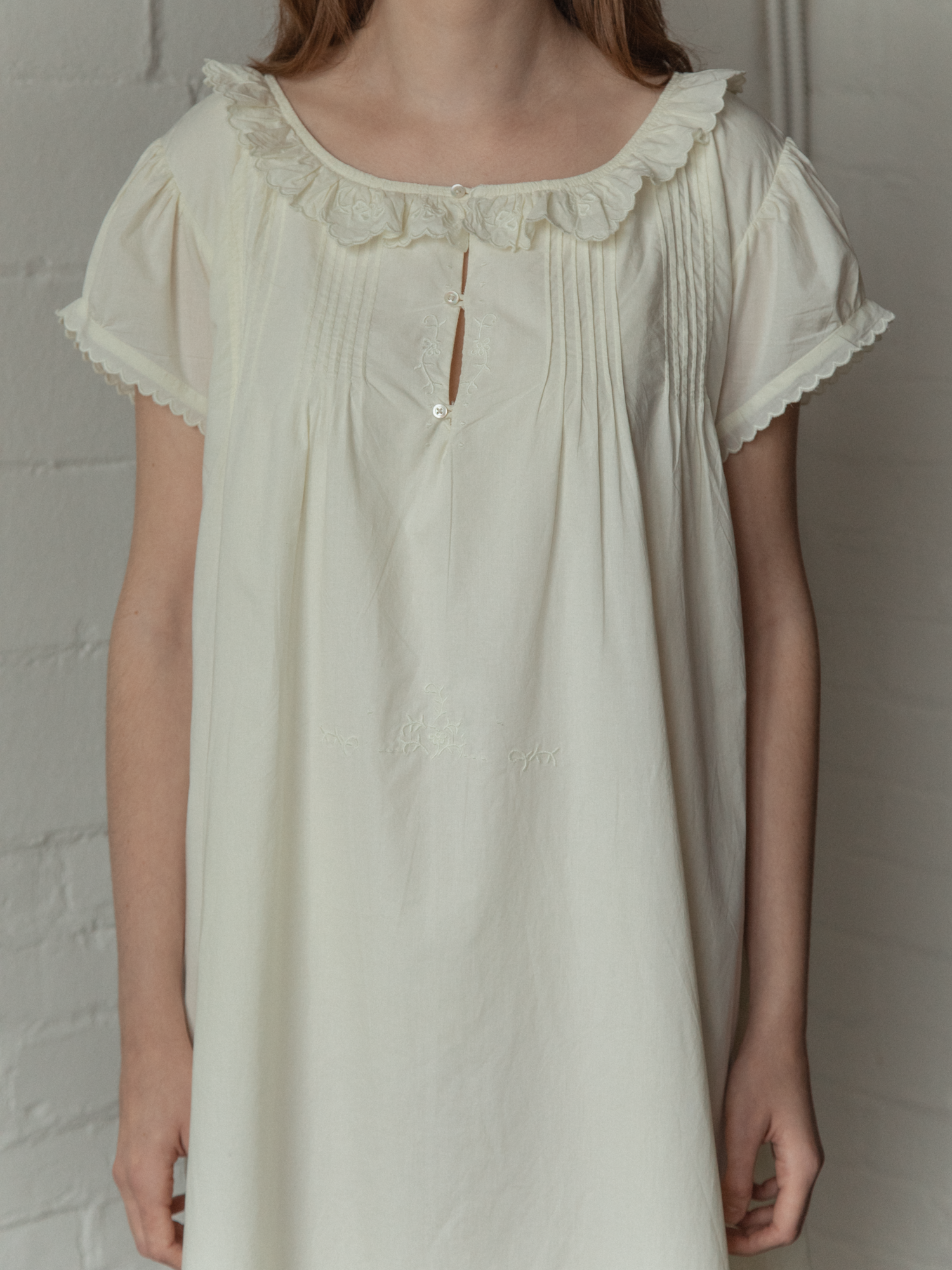 Model wearing the Clover Dress in Butter by Gillian Stevens, front detail showing ruffle neckline and pin tucks