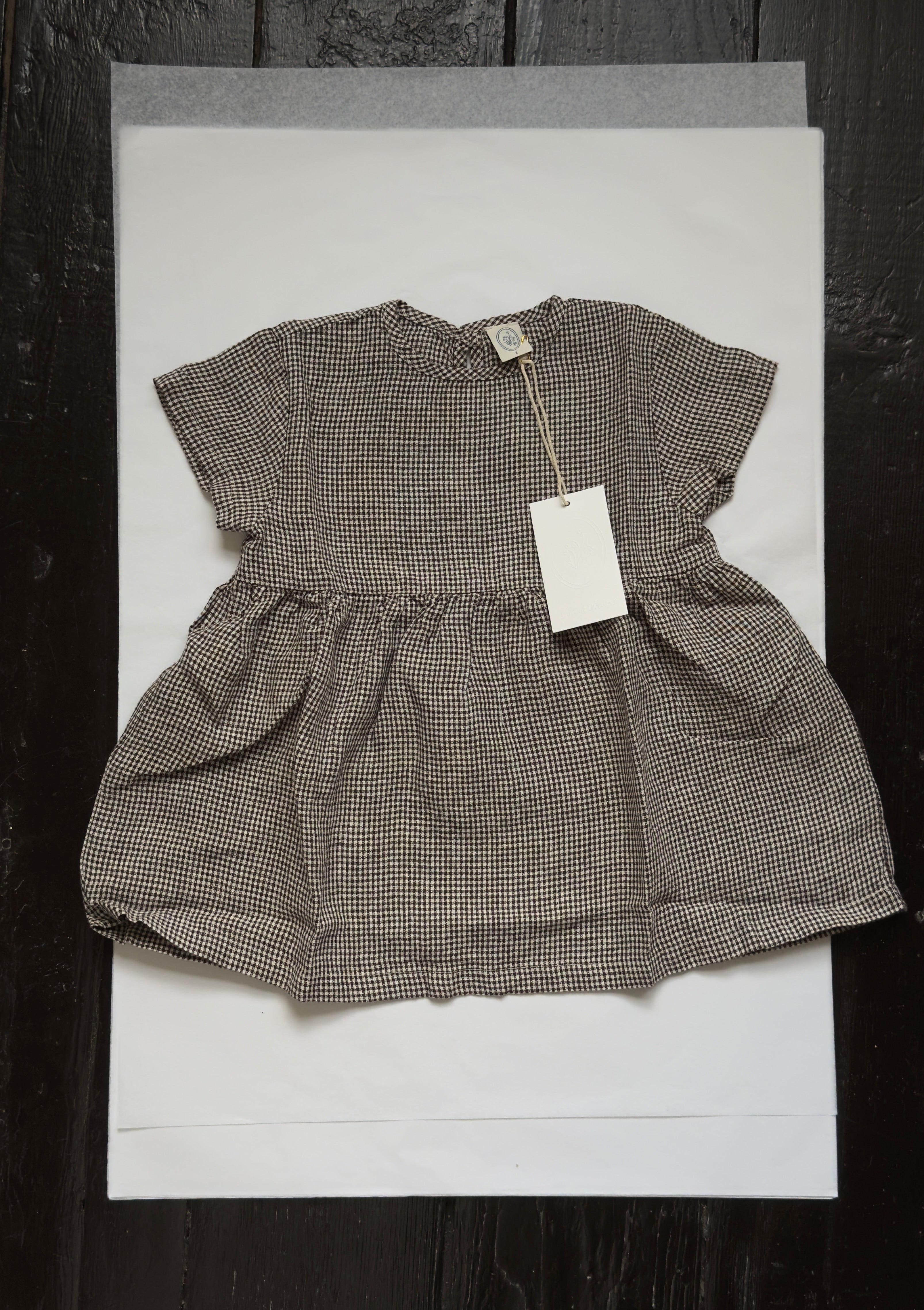 Flat-lay of the Mini Aya in Espresso Gingham by Gillian Stevens, showing gathered skirt and short sleeves
