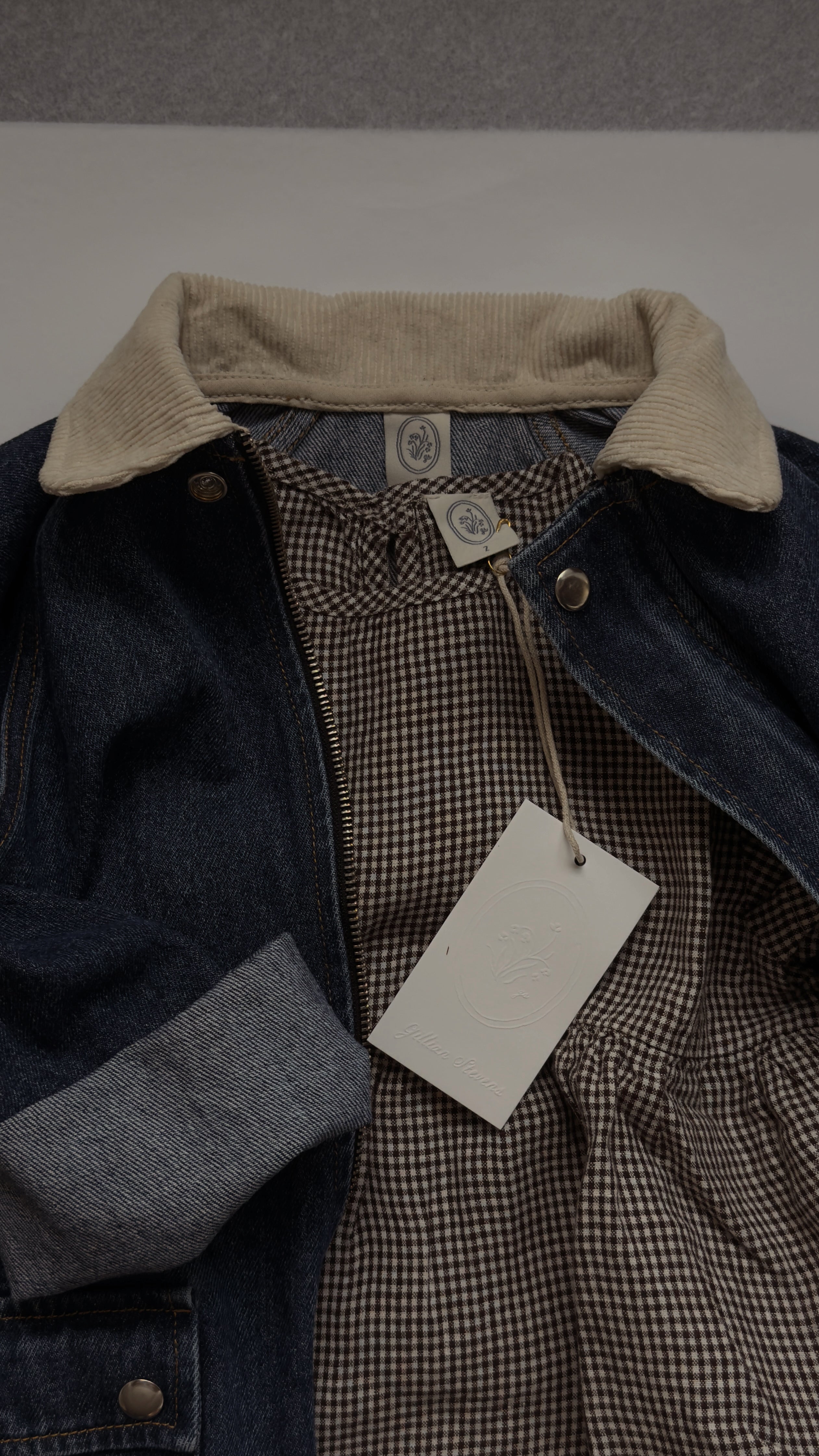 Close-up of the Mini Aya in Espresso Gingham by Gillian Stevens, layered under a denim jacket showing collar and tag detail