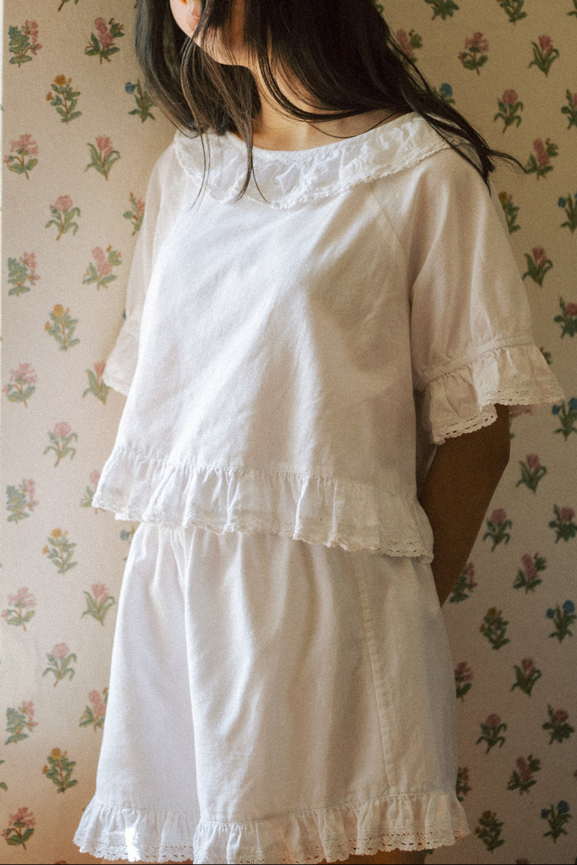 Model wearing the Arlette Top in Salt by Gillian Stevens, front view showing lace collar and ruffle hem detail