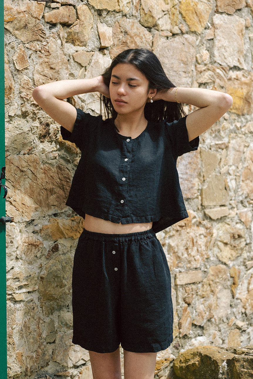 Model wearing the Wren Top in Noir by Gillian Stevens, front view against a stone wall
