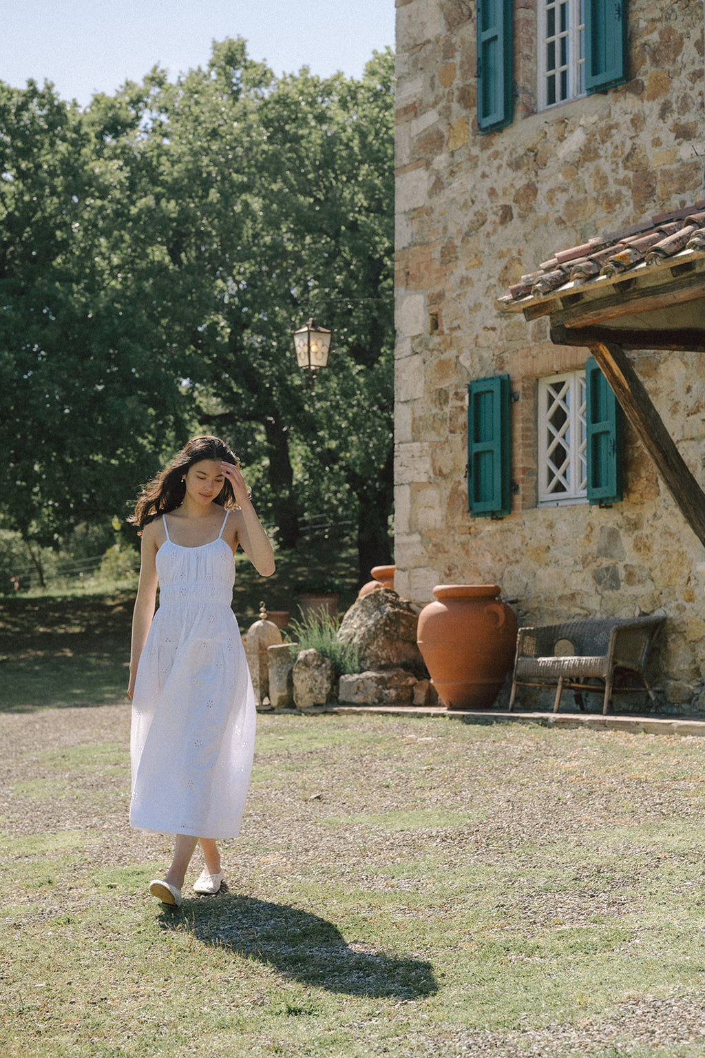 Model walking outdoors in the Alessandra Dress in Salt by Gillian Stevens, rustic stone villa setting