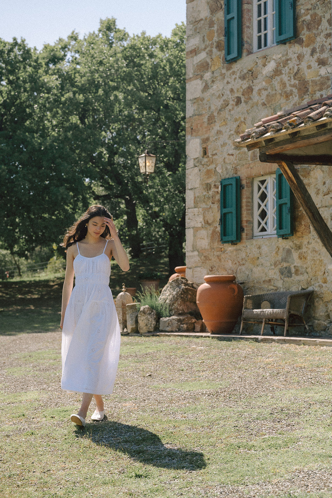 Model walking outdoors in the Alessandra Dress in Salt by Gillian Stevens, rustic stone villa setting