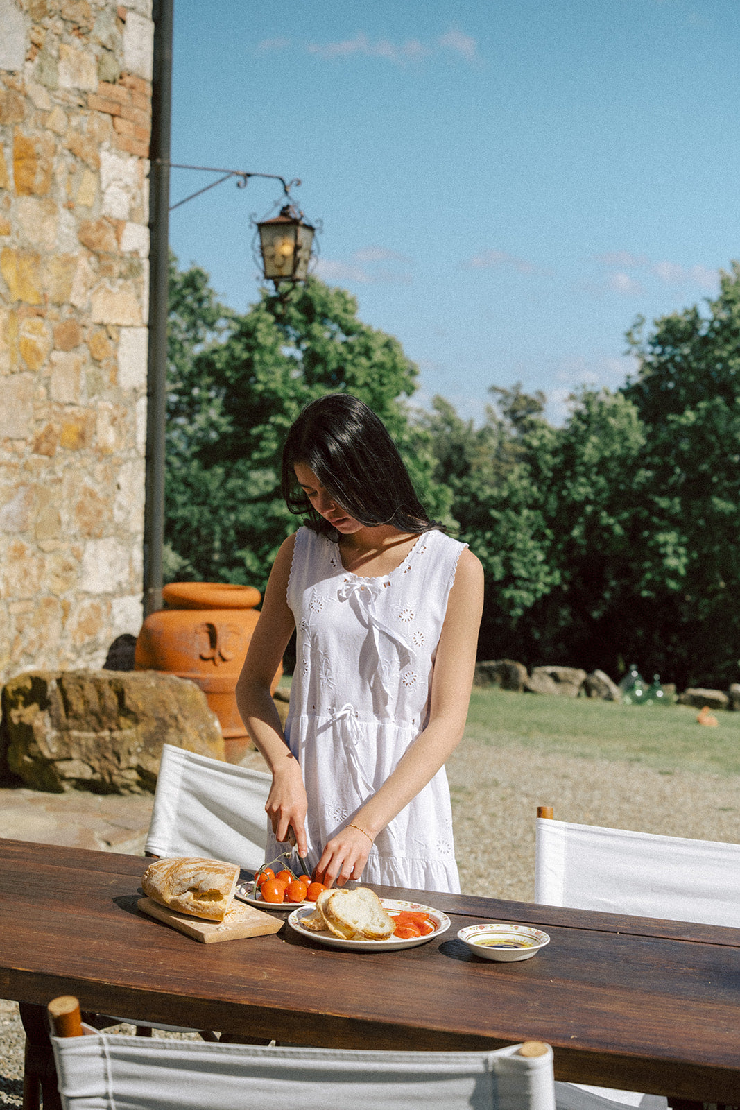 Model wearing the Plum Dress in Salt by Gillian Stevens, styled outdoors at a rustic stone villa