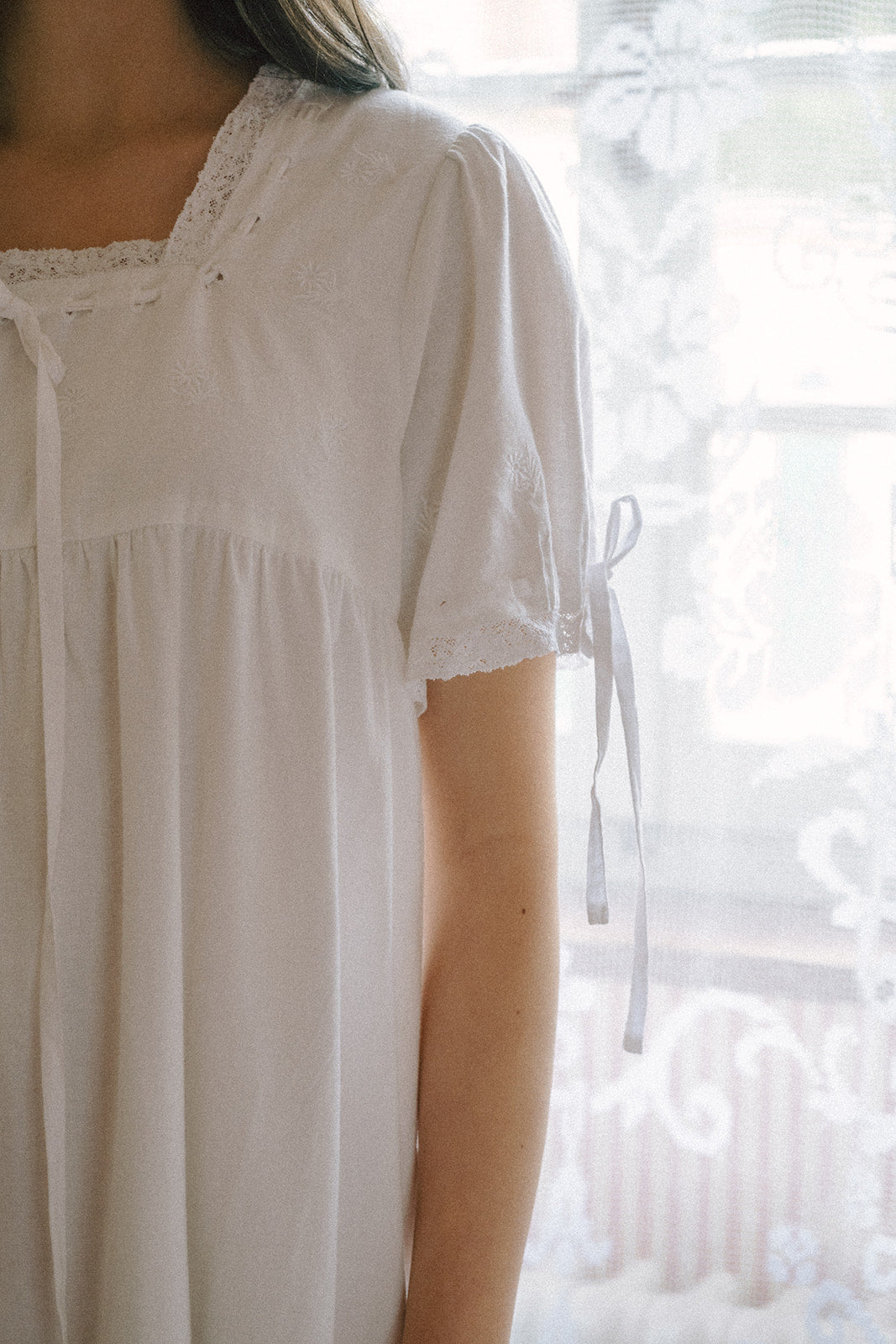 Close-up of model in the Dace Dress in Salt by Gillian Stevens, showing lace neckline and sleeve tie detail
