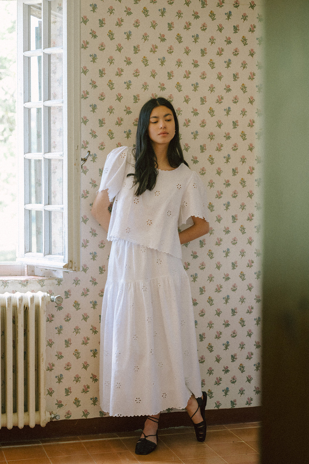 Model wearing the Stella Top in Salt by Gillian Stevens, styled with a white eyelet skirt, front view
