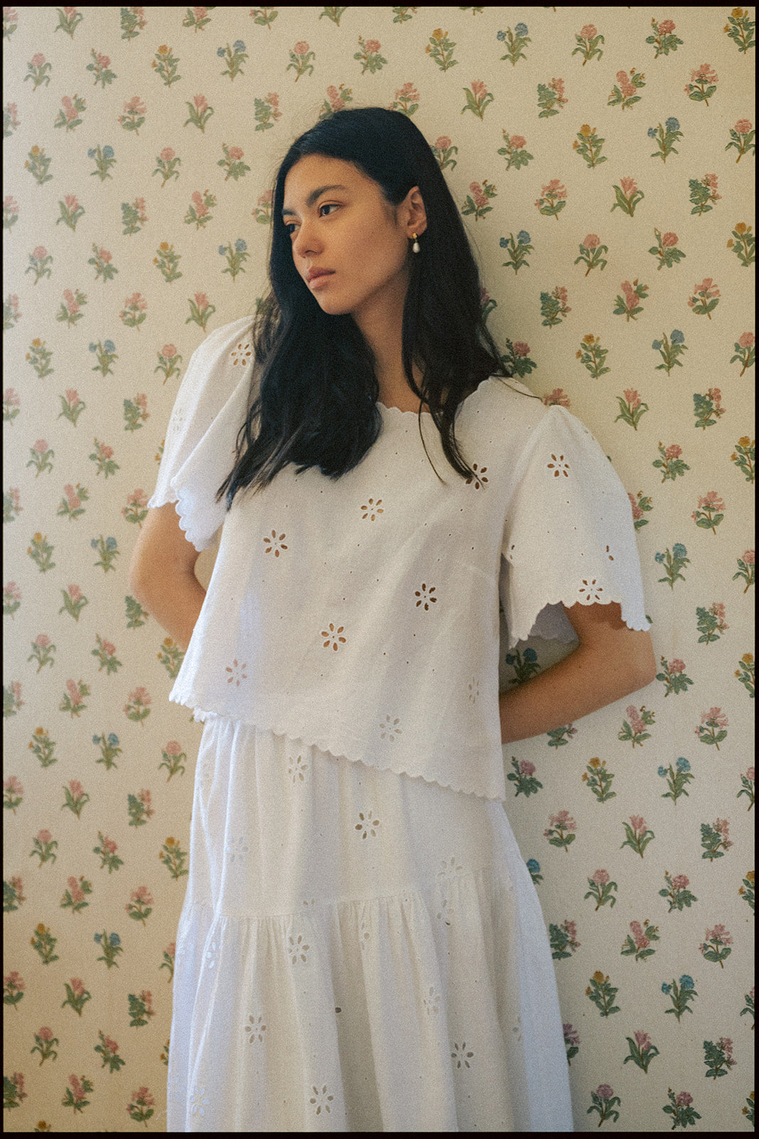 Model wearing the Stella Top in Salt by Gillian Stevens, front view against floral wallpaper
