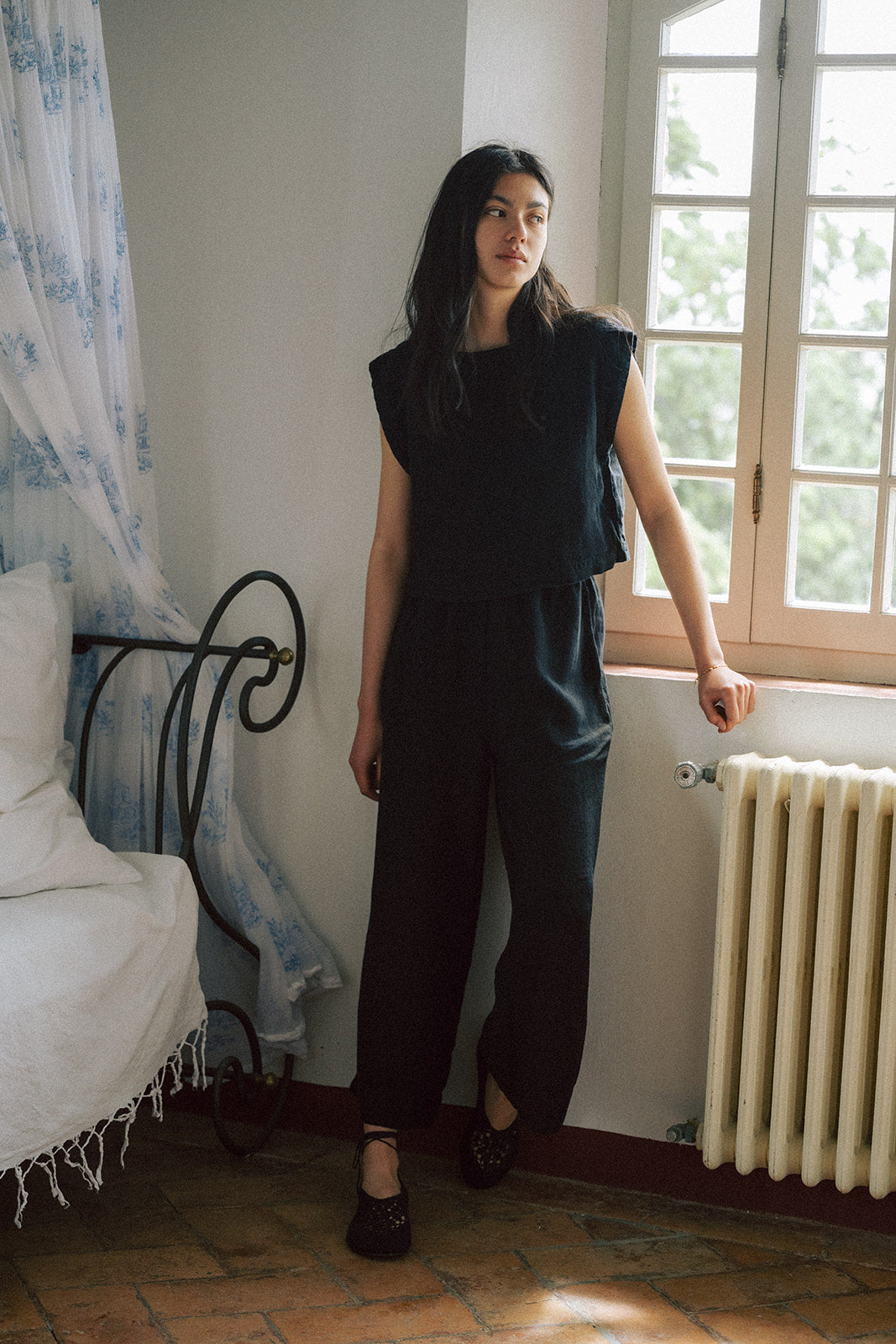 Model wearing the Ines Pant in Noir by Gillian Stevens, full-length front view in a sunlit room