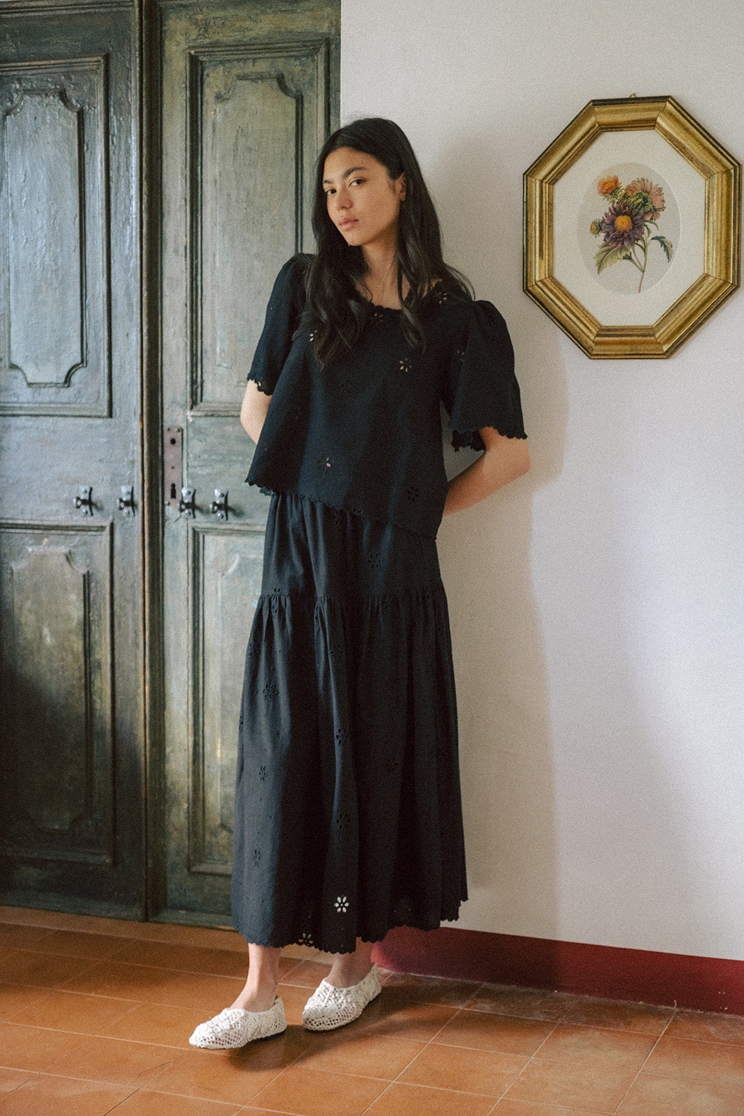 Model wearing the Stella Skirt in Noir by Gillian Stevens, paired with a black top, front view in a heritage interior