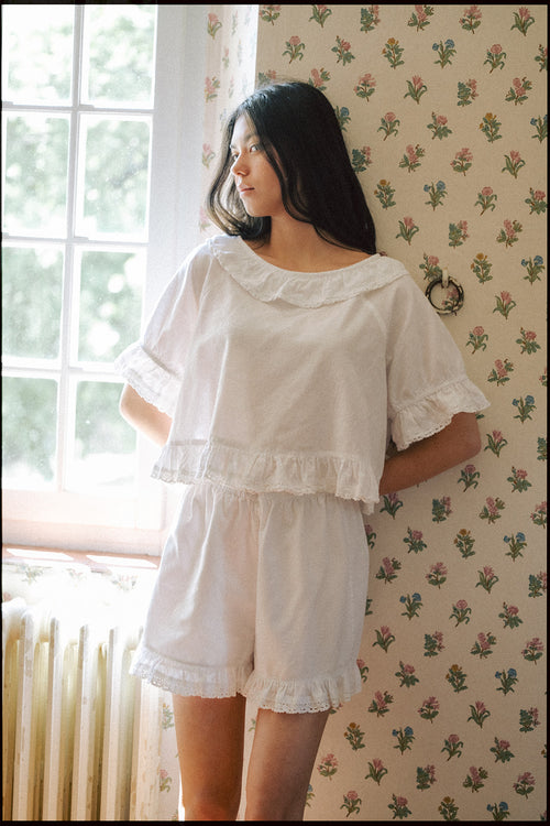 Model wearing the Arlette Short in Salt by Gillian Stevens, back view against floral wallpaper