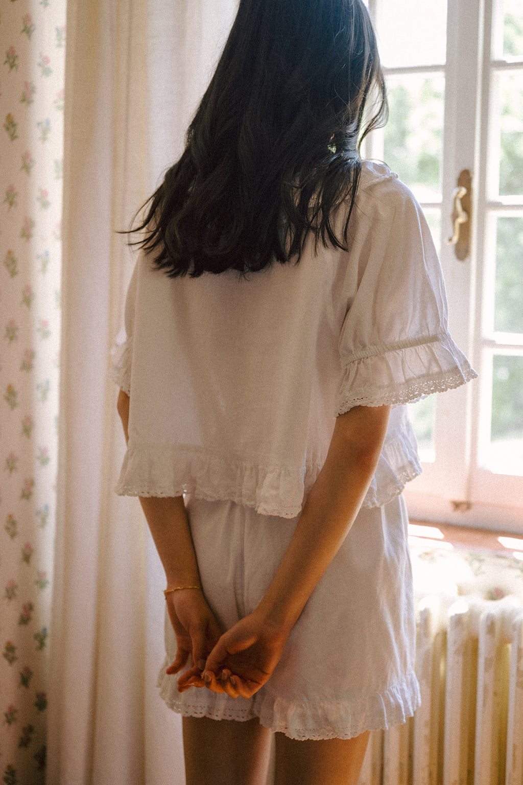 Model wearing the Arlette Short in Salt by Gillian Stevens, back view by a sunlit window