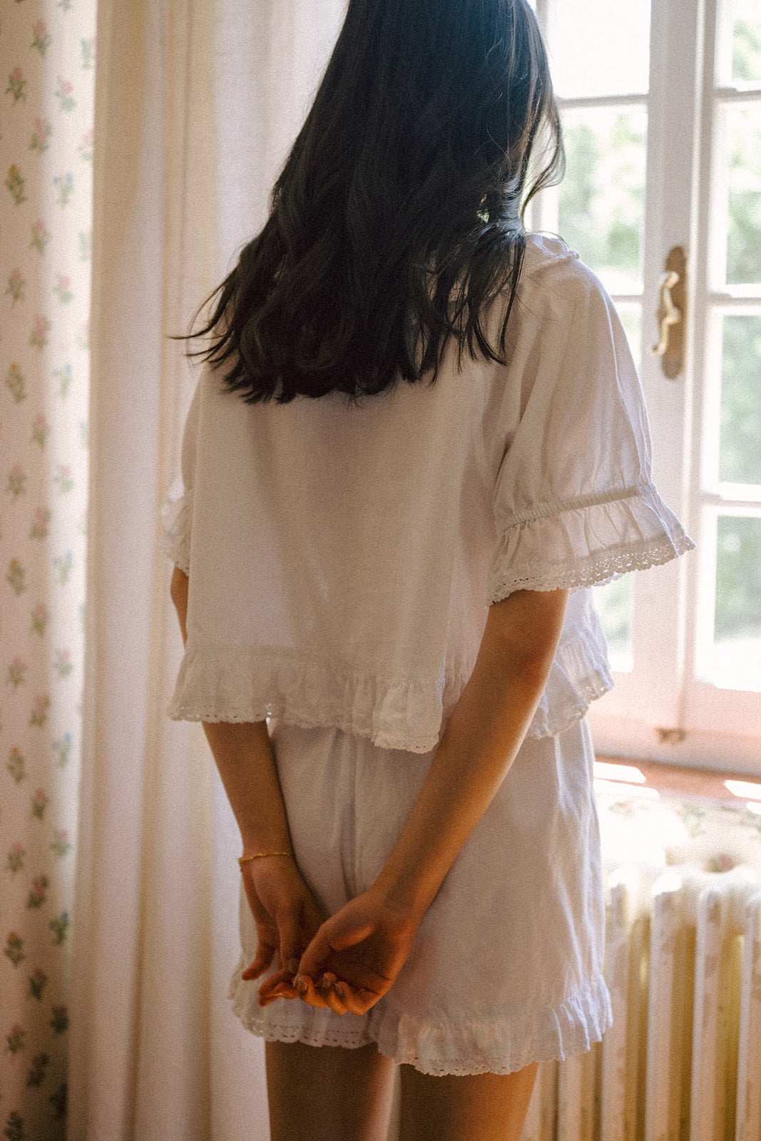 Model wearing the Arlette Short in Salt by Gillian Stevens, back view by a sunlit window
