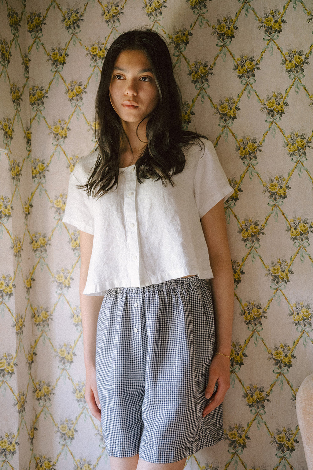 Model wearing the Wren Top in Salt by Gillian Stevens, front view against floral wallpaper