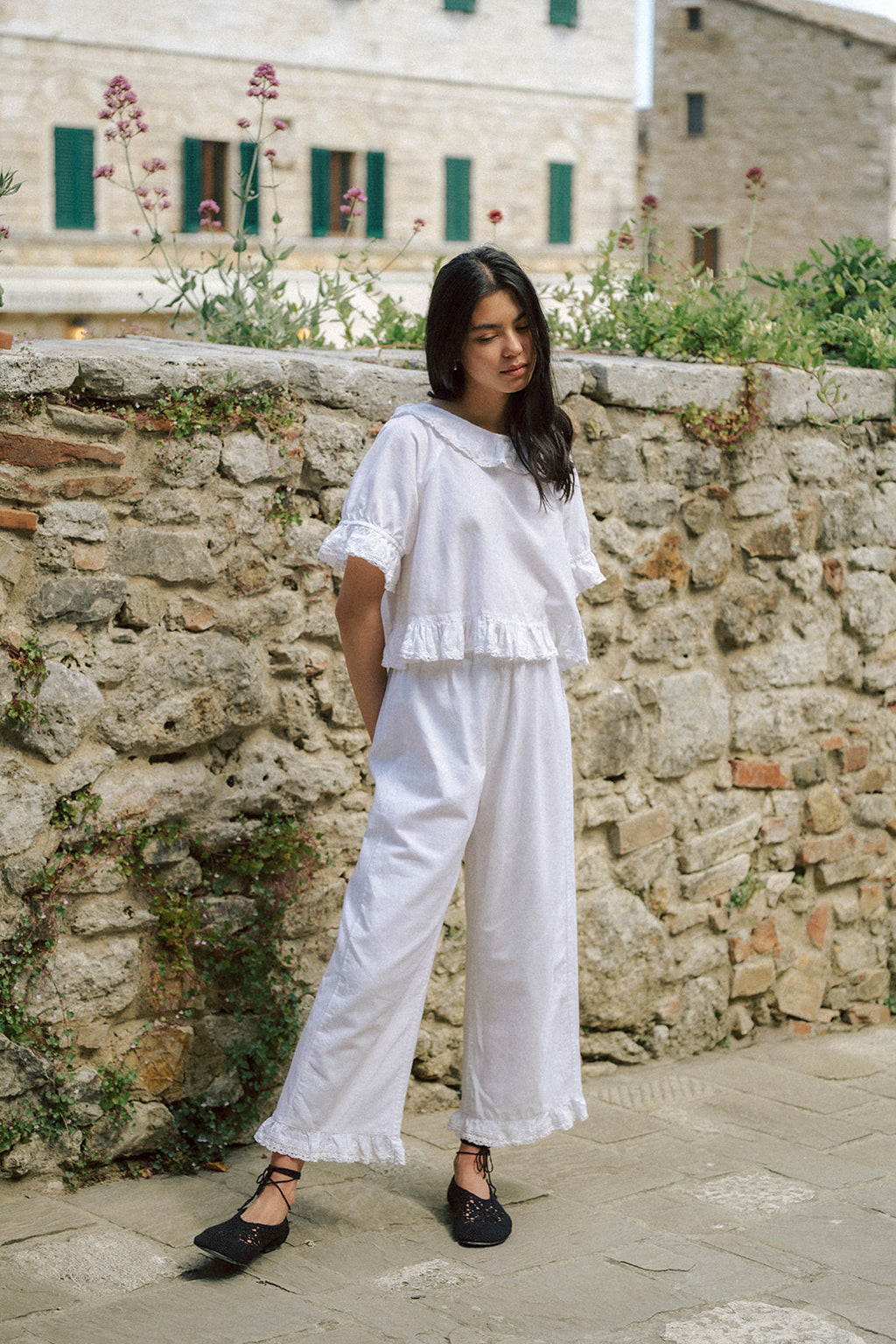 Model wearing the Arlette Pant in Salt by Gillian Stevens, full-length front view against a stone wall