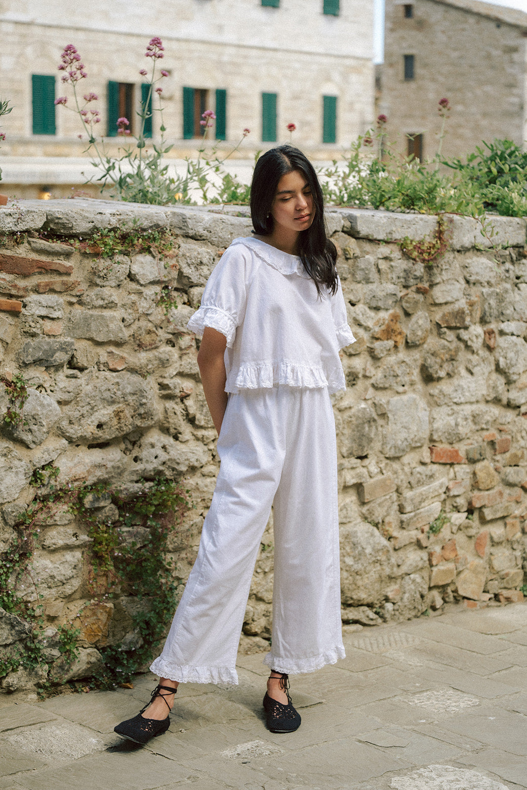 Model wearing the Arlette Pant in Salt by Gillian Stevens, full-length front view against a stone wall