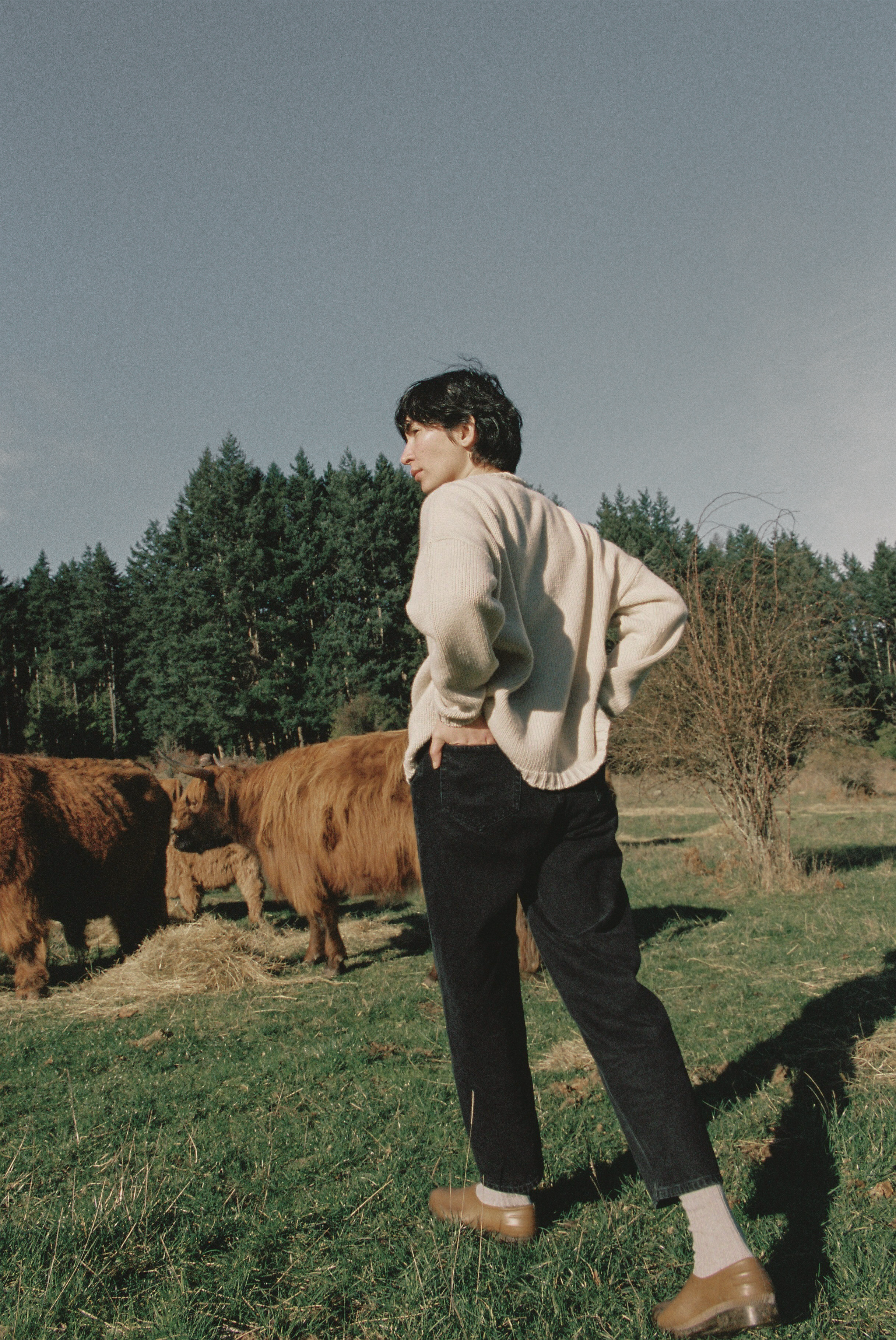 Model wearing the Dara Jean in Noir by Gillian Stevens, back view in a rural field setting