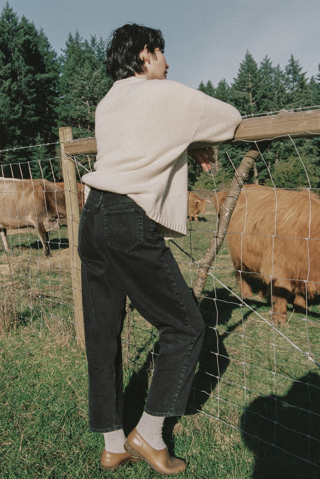 Model wearing the Dara Jean in Noir by Gillian Stevens, back view at a farm fence
